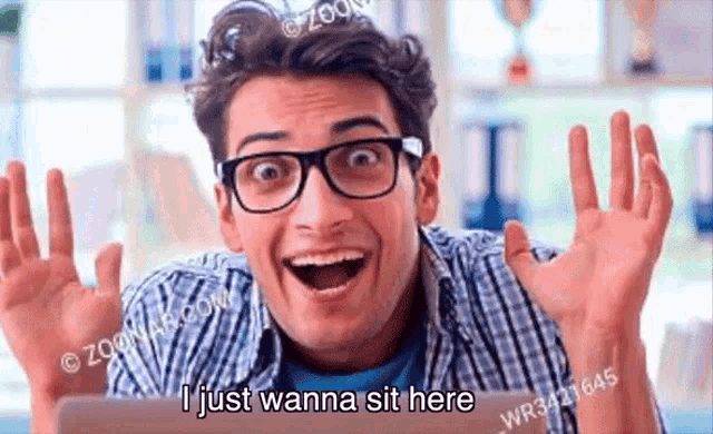 a young man wearing glasses is sitting in front of a tablet computer and making a funny face .