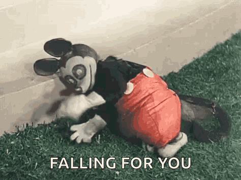 a stuffed mickey mouse is crawling on the grass and falling for you .