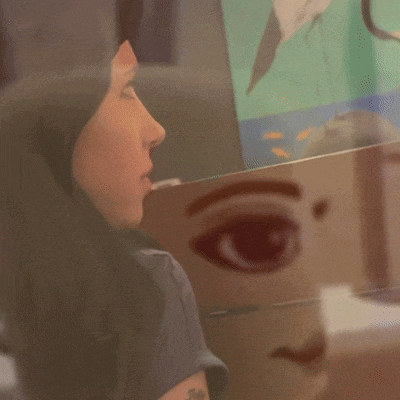 a painting of a woman 's face is reflected in a wall