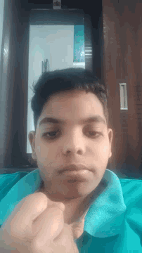 a boy in a blue shirt looks at the camera