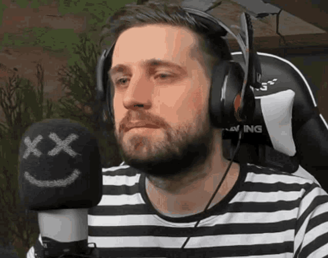 a man wearing headphones stands in front of a microphone that has a smiley face on it