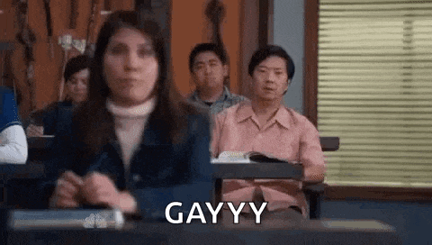 a group of people are sitting at desks in a classroom and one of them is making a funny face .