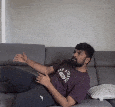 a man is laying on a couch wearing a gap athletic t-shirt