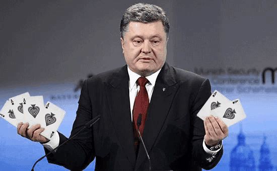 a man in a suit and tie holds four playing cards in front of a microphone