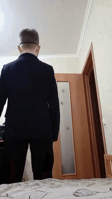 a man in a suit and glasses stands in front of a door