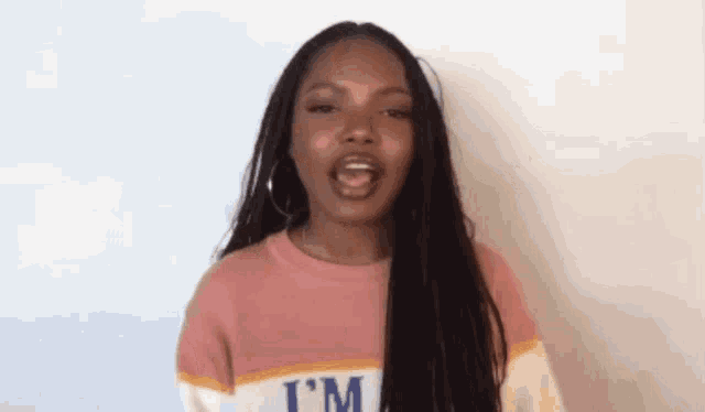a woman with long hair is wearing a pink and white striped sweater and earrings .