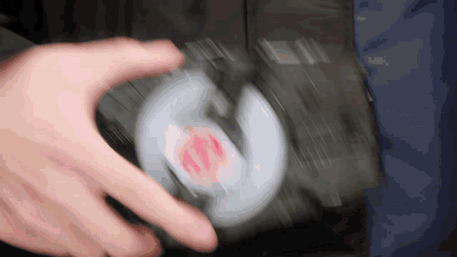 a person 's hand is holding a spinner with a red circle on it