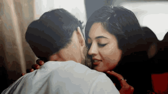 a man is kissing a woman on the cheek in a room
