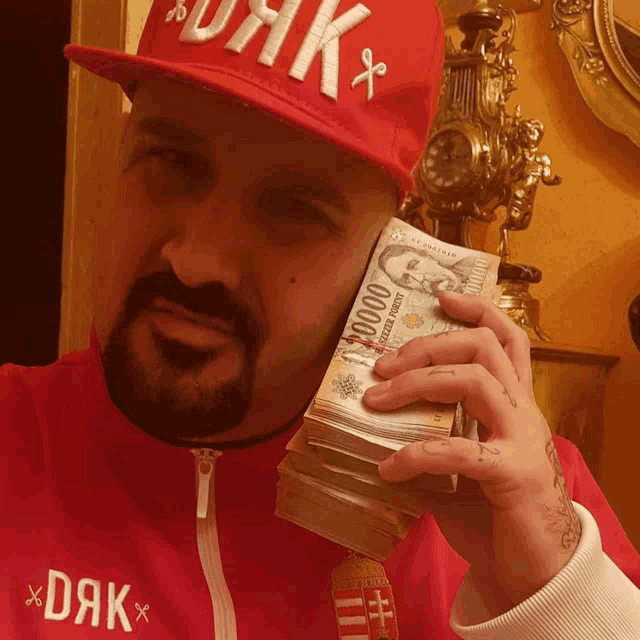 a man wearing a red hat and holding a stack of money