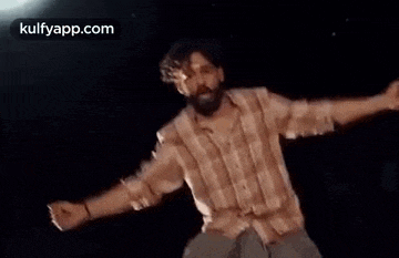 a man is dancing with his arms outstretched in the dark .