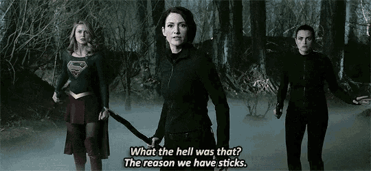 three women are standing next to each other in a foggy forest and one of them is holding a sword .