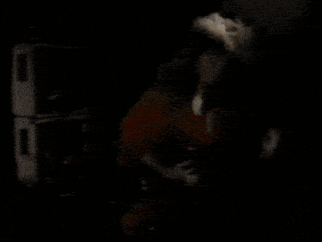 a person is playing a guitar in a dark room with a lot of flames coming out of it .