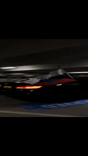 a black car is driving down a parking lot with a handicapped parking spot