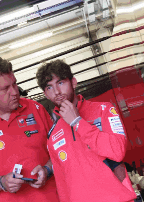 a man wearing a red shirt with monster on it stands next to another man