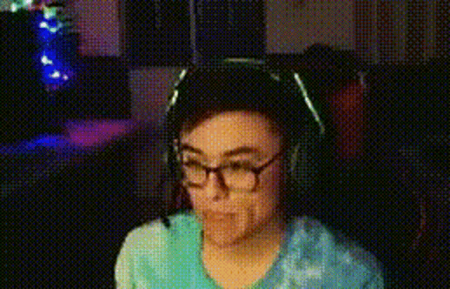 a man wearing glasses and headphones is looking at a computer screen .