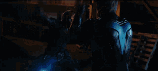 a man in a black jacket is standing in the dark with a blue light shining on him .