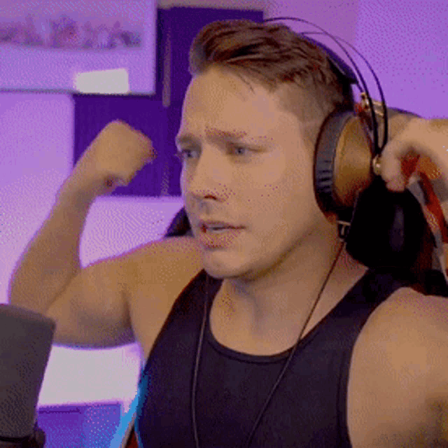 a man wearing headphones is flexing his muscles in front of a laptop