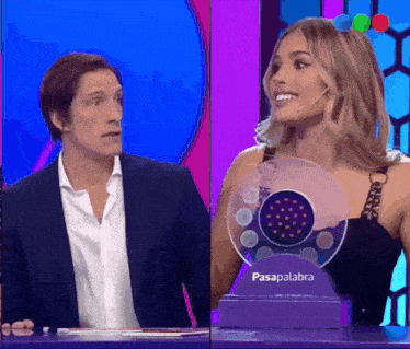 a man and a woman are sitting in front of a purple item that says pasapalabra on it