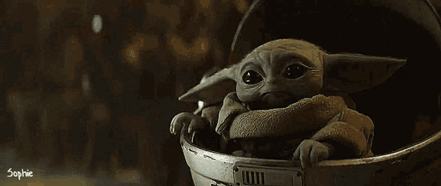 a baby yoda from star wars is sitting in a metal bucket .