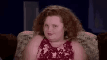 a young girl is sitting in a chair and making a face .
