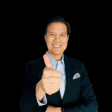 a man in a suit and blue shirt is giving a thumbs up