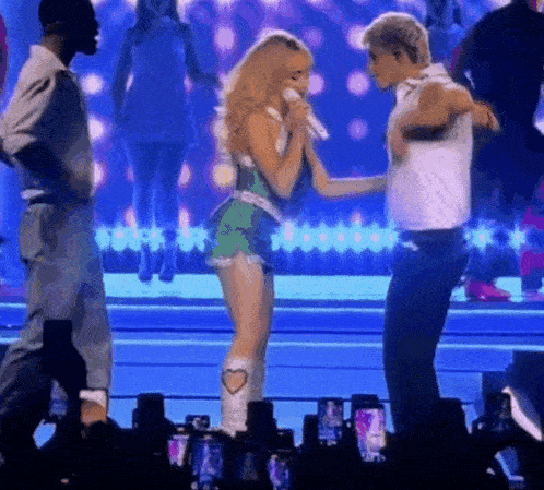 a woman singing into a microphone while standing next to a man