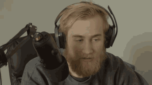 a man with a beard is wearing headphones and looking at the camera