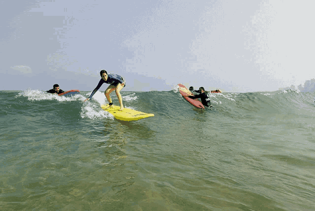 a woman is riding a wave on a yellow surfboard that says ' hawaii ' on it