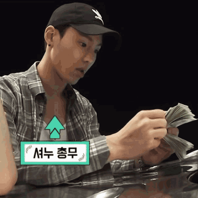 a man wearing a black adidas hat is holding a bunch of money in his hands