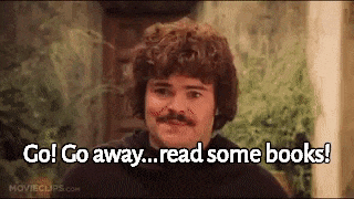 a man with curly hair and a mustache is talking about reading books .
