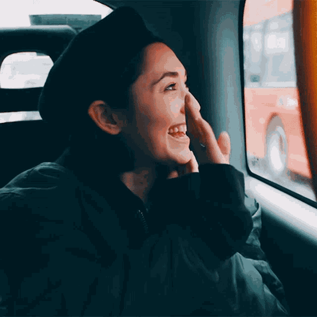 a woman wearing a black beret is smiling while looking out of a car window