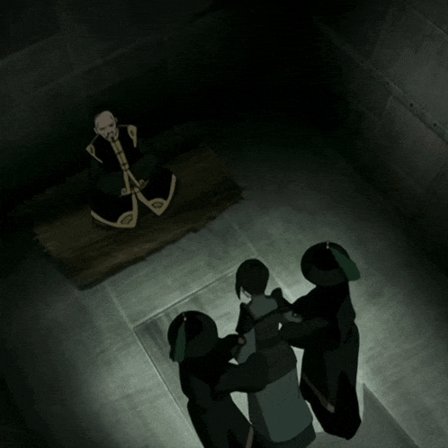 a man in a black robe sits at a table surrounded by two women