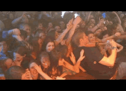 a crowd of people at a concert with a man holding a microphone in front of them
