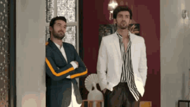 two men in suits and striped shirts are standing next to each other in a room .