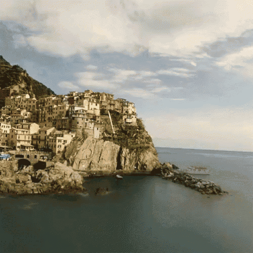 a small town sits on top of a rocky cliff overlooking the ocean