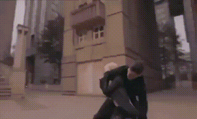 a man is holding a woman in his arms in front of a building in a city .