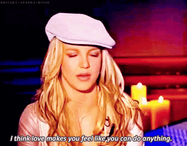 britney spears is wearing a white hat and saying i think love makes you feel like you can do anything