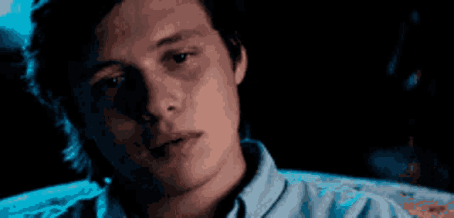 a close up of a young man 's face in a dark room .