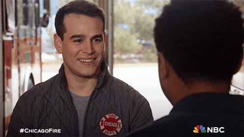 a man wearing a jacket that says chicago fire is talking to another man