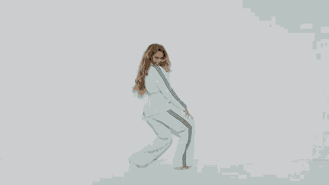 a woman in a blue suit and heels is dancing against a white background .