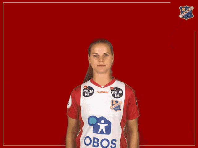 a woman in a red and white hummel jersey holds her arm up