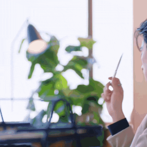 a blurry picture of a person holding a pen with a plant in the background