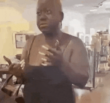a woman in a black tank top is standing in a room holding a glass of wine .