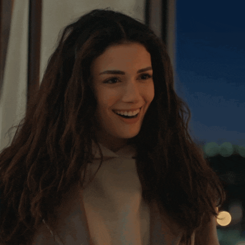 a woman with long hair is smiling and looking out a window