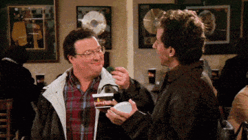 a man in a plaid shirt is feeding another man something