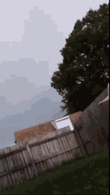 a person is jumping over a wooden fence with a house in the background