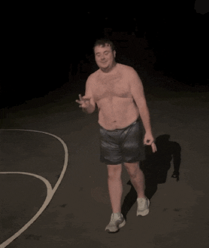 a man without a shirt is dancing on a basketball court