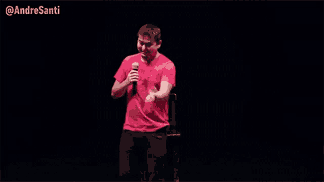 a man in a red shirt is holding a microphone in front of a black background ..