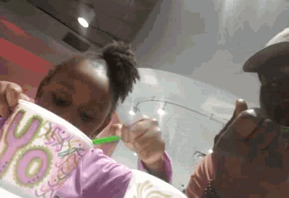 a little girl is eating out of a cup that says ' oops ' on it