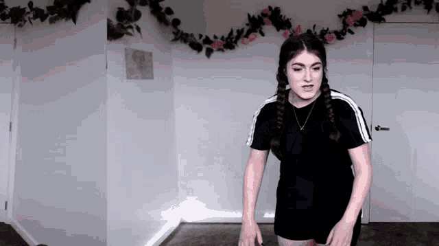 a woman in a black shirt and shorts stands in front of a white wall